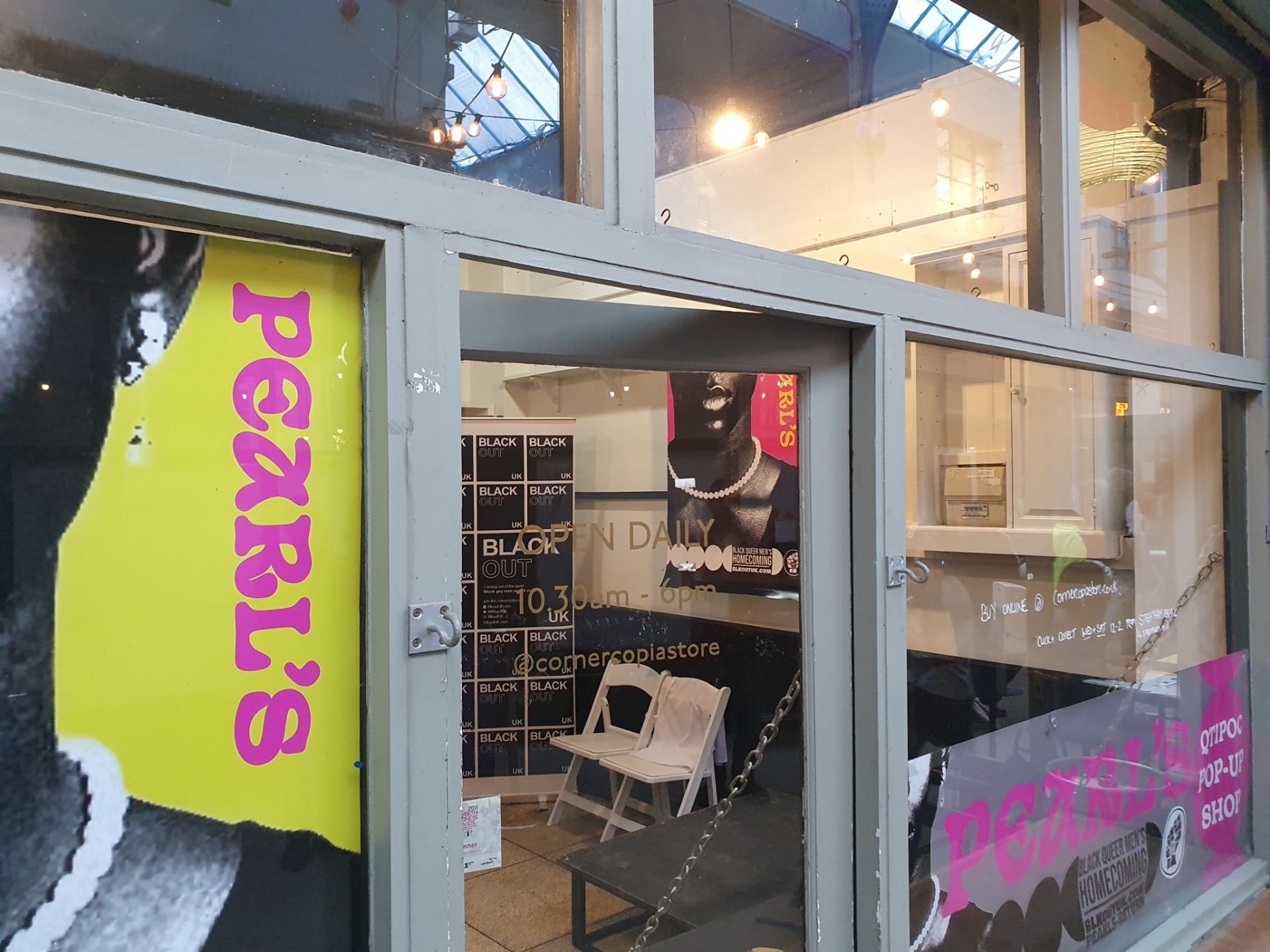 The Pearl's QTIPOC pop-up shop front in Brixton Market — pink Pearl's lettering and BLACK OUT UK banners in the windows
